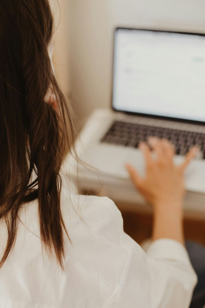 Femme de dos travaillant sur ordinateur.