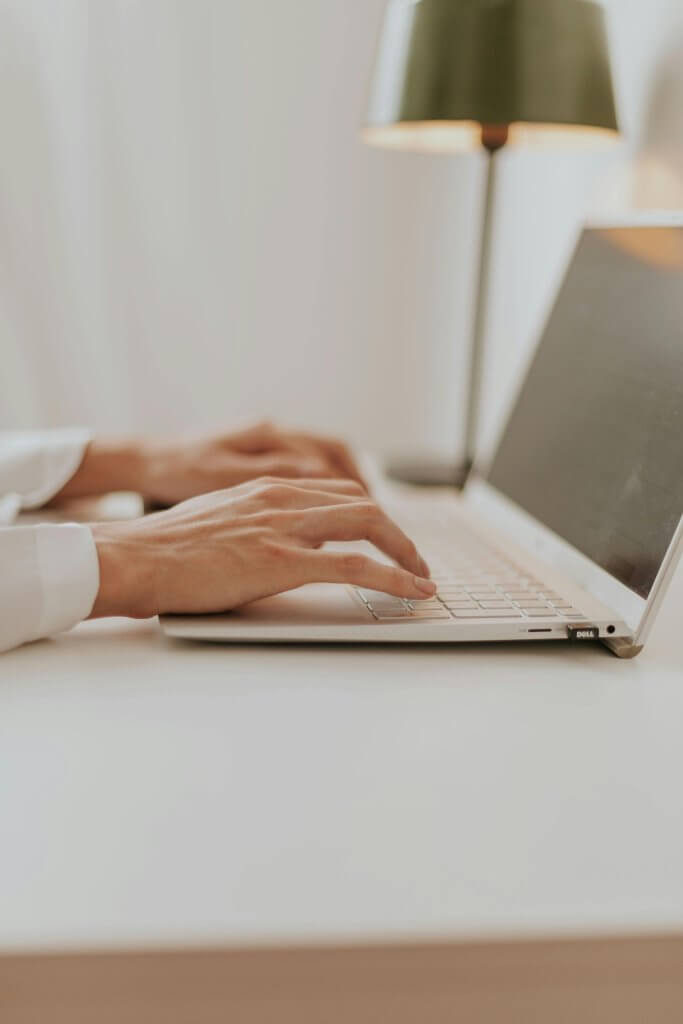 Mains de femme tapant sur le clavier d'un ordinateur portable.